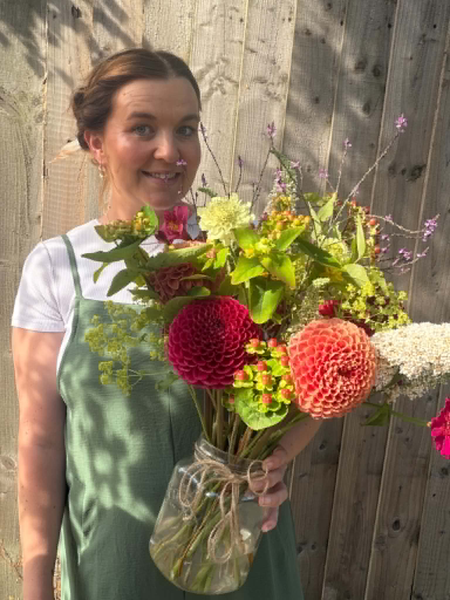 Fi holding a hand-tied bouquet of dahlias and wildflowers