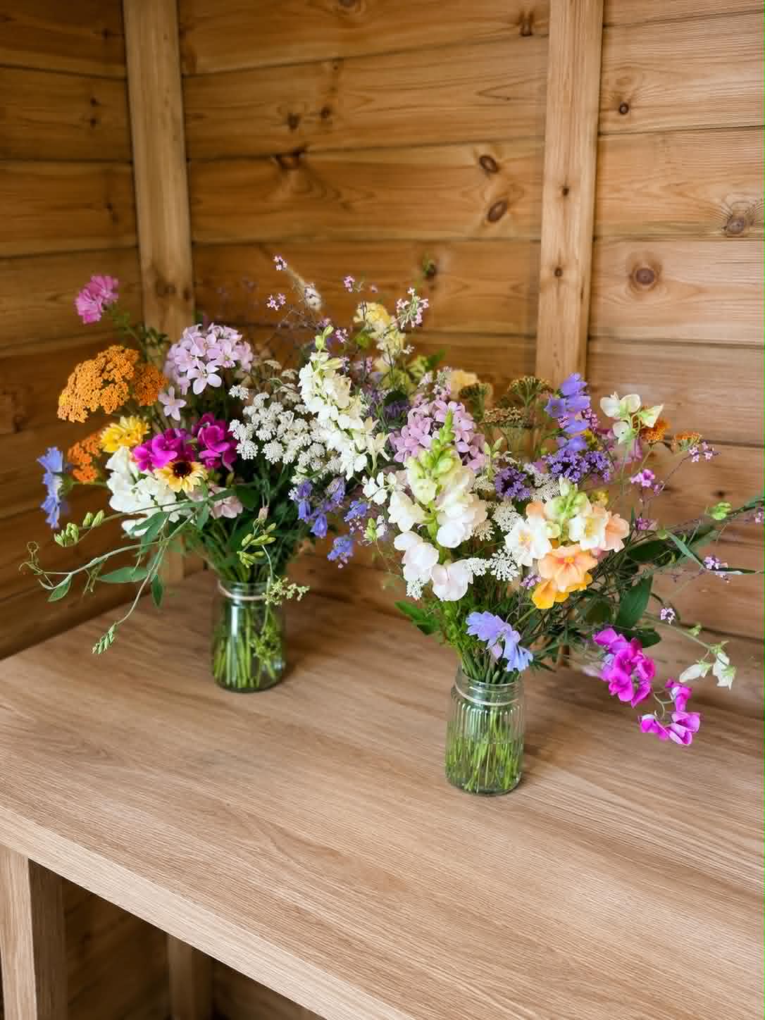 Two jam jar posies on a garden bench
